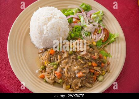 Pollo con salsa di cipolla, insalata e riso bianco, tipico piatto gambiano. Foto Stock