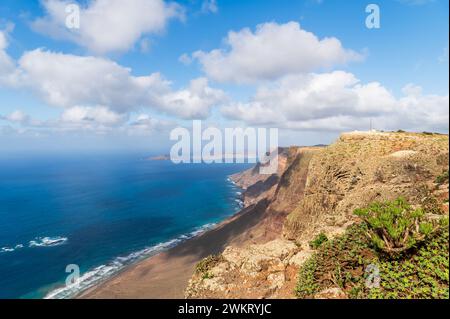 Ampie vedute di Playa Famara, Lanzarote, con le sue sabbie dorate abbracciate da acque azzurre e scogliere spettacolari, un paradiso per i surfisti. Foto Stock