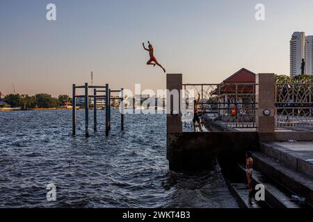 Bangkok, Thailandia. 22 febbraio 2024. I ragazzi saltano nel fiume Chao Phraya sotto il ponte Rama VIII a Bangkok, Thailandia, giovedì 22 febbraio 2024. (Credit Image: © Andre Malerba/ZUMA Press Wire) SOLO PER USO EDITORIALE! Non per USO commerciale! Foto Stock