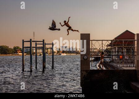 Bangkok, Thailandia. 22 febbraio 2024. I ragazzi saltano nel fiume Chao Phraya sotto il ponte Rama VIII a Bangkok, Thailandia, giovedì 22 febbraio 2024. (Credit Image: © Andre Malerba/ZUMA Press Wire) SOLO PER USO EDITORIALE! Non per USO commerciale! Foto Stock