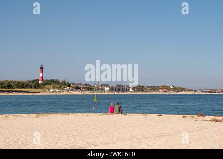 Coppia sulla spiaggia sud che guarda lo skyline di Hornum e il faro, Sylt Island, North Frisia, Schleswig-Holstein, Germania Foto Stock