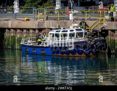 Una piccola barca da lavoro ormeggiata lungo le mura del porto nel porto di Portsmouth. Foto Stock