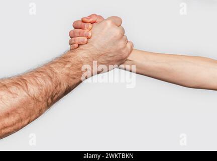 Uomo e donna con le mani strette si impegnano nel braccio di ferro. Sfondo grigio. Lotta uomo e donna Foto Stock