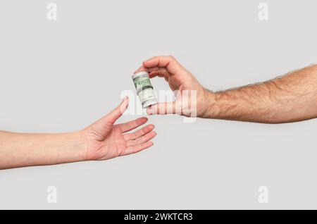 Dollari di trasmissione da mano a mano, sfondo grigio. Concetto di investimento, donazioni, beneficenza Foto Stock