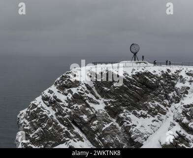 Scogliere innevate con persone sulla cima della montagna vicino a una statua Foto Stock