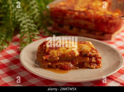 Una lasagna in un piatto su una tovaglia a scacchi Foto Stock