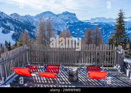 Sedie a sdraio rosse vuote e paesaggio invernale con Dolomiti innevate a Plan de Corones, Italia Foto Stock