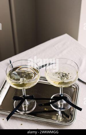 Bevande natalizie, due spumanti in bicchieri decorati con nastro in raso Foto Stock