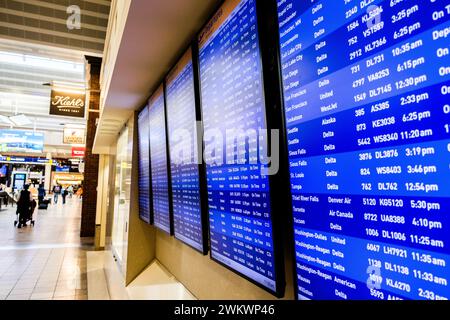 I viaggiatori aerei e l'esposizione degli arrivi e delle partenze al Minneapolis-St Aeroporto Paul, USA (MSP) durante una tipica giornata di viaggio in aeroporto. Foto Stock