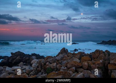 La luna piena sorge sopra il surf a Point Pinos, Monterey Bay, California Foto Stock