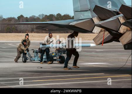 Gli aviatori assegnati al 1st Fighter Wing caricano un missile AIM-120 Advanced Medium Range Air-to-Air verso un F-22 Raptor per il caricamento alla Joint base Langley-Eustis, Virginia, 8 febbraio 2024. Il 1st Fighter Wing si abbinò al 6th Airlift Squadron per testare le capacità congiunte, che si concentravano su manovre di combattimento integrate e operazioni di rifornimento. (Foto U.S. Air Force di Airman 1st Class Ian Sullens) Foto Stock