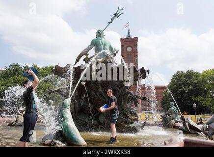 I partecipanti affamati d'acqua alla battaglia d'acqua di quest'anno alla fontana Nettuno di Berlino si rinfrescano nelle temperature estive il 17 giugno 2018. Benne e grandi Foto Stock