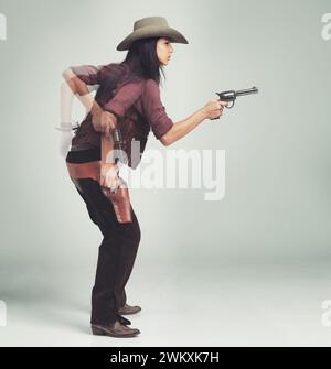 WESTERN, cowboy e donna con pistola in studio per il movimento, la velocità e il tiro in piedi pronti. Persona femminile, arma ed espressione seria con Foto Stock