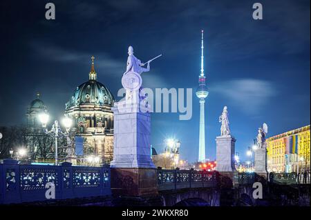 Ponte con statue di pietra vicino alla cattedrale di Belin illuminata di notte, Germania Foto Stock