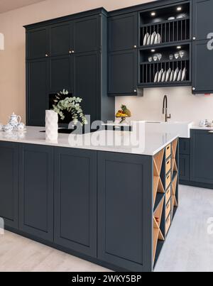 Una cucina moderna ed elegante caratterizzata da eleganti armadi grigio scuro e ripiani in marmo bianco Foto Stock