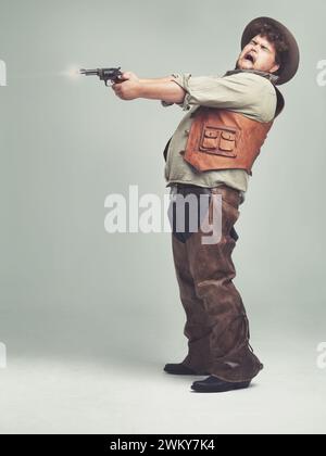 Cowboy, uomo e fucile in studio, pistola o combattimento occidentale isolati su uno spazio di mockup su sfondo bianco. Più grande, divertente criminale e persona con Foto Stock