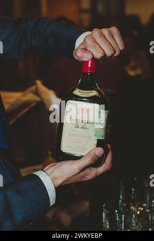 Un uomo che versa alcol da una bottiglia in un bicchiere. Foto Stock
