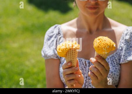 Le mani delle donne tengono un gelato rinfrescante in coni di waffle con un pizzico di saporito sapore di limone. Con spazio di copia Foto Stock