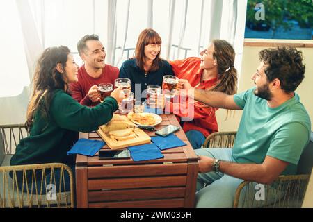 Gruppo di amici allegri che brindano con bicchieri da birra a una festa casalinga informale - concetto di divertimento e amicizia Foto Stock