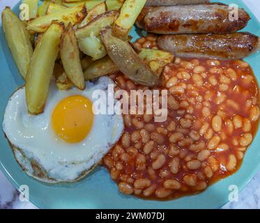 Un piatto di patatine fritte fatte in casa con salsicce, uova fritte e fagioli Foto Stock