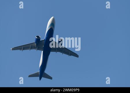 Parte inferiore di un jet commerciale che vola sopra, un Airbus A320 Neo su uno sfondo blu del cielo. Foto Stock