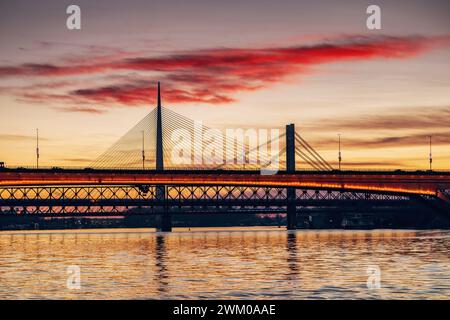 Magnifico tramonto sul fiume Sava a Belgrado, Serbia, illuminando il ponte e il paesaggio urbano circostante con un bagliore dorato. Foto Stock