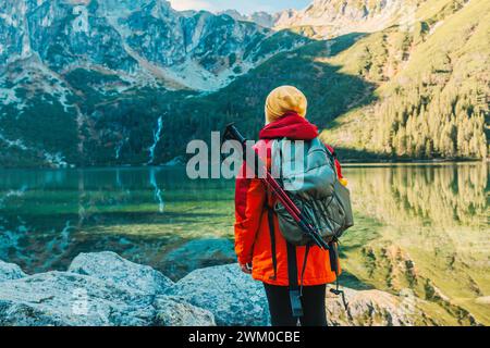 Donna turistica anni '50 con uno zaino in piedi sulla cima della montagna e goditi la splendida vista delle montagne del lago Morskie Oko. Escursioni, viaggi e. Foto Stock