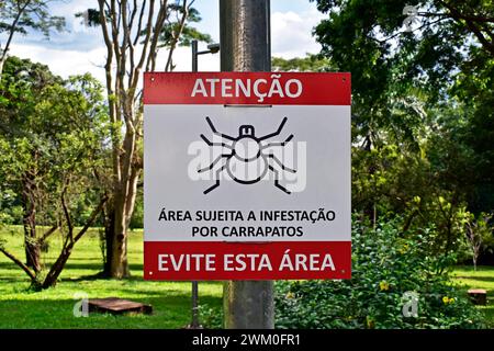Cartello segnaletico in portoghese con indicazione "attenzione, area soggetta a infestazione da zecche, evitare questa zona" Foto Stock