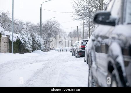 Pali di neve sulla strada, strade non pulite, auto parcheggiate sul lato della strada. Foto Stock