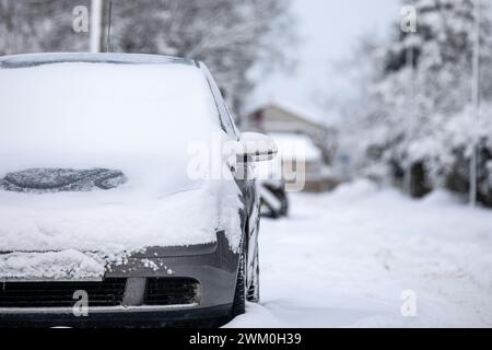 Pali di neve sulla strada, strade non pulite, auto parcheggiate sul lato della strada. Foto Stock