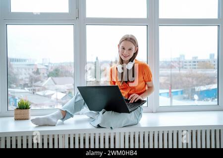 Felice freelance seduto con un laptop sul davanzale Foto Stock
