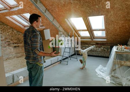 Padre che guarda la figlia che sta facendo il tappeto in una camera in fase di ristrutturazione Foto Stock