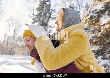 Giovane donna che si diverte a cavalcare con l'uomo nella foresta invernale Foto Stock