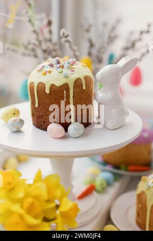 Torta decorata con spruzzette di zucchero vicino al giocattolo coniglietto pasquale Foto Stock