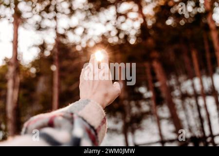 Mano di donna che si avvicina alla luce del sole Foto Stock