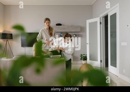 Ragazza che prepara la borsa per la scuola vicino alla madre a casa Foto Stock