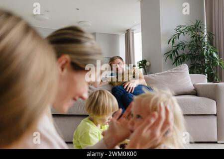 Uomo felice che guarda la famiglia nel salotto di casa Foto Stock