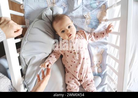 Bella bambina sdraiata nella culla vicino alla madre a casa Foto Stock