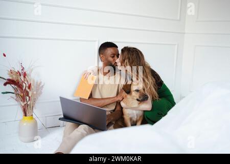 Coppia che si baciava vicino al cane a casa Foto Stock