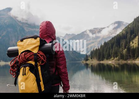 Giovane donna con zaino in piedi di fronte al lago Vilsalpsee e alle montagne del Tirolo, Austria Foto Stock