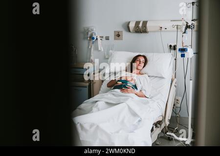 Sorridente donna incinta con le mani sullo stomaco sdraiato a letto in ospedale Foto Stock