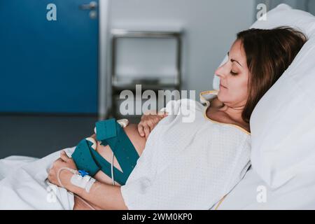 Donna incinta con mani sullo stomaco sdraiato in ospedale Foto Stock