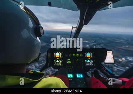 Pilota di servizio medico di emergenza elicottero sorvolando il paesaggio al crepuscolo. Temi medicina d'emergenza, soccorso e aiuto d'emergenza. Foto Stock