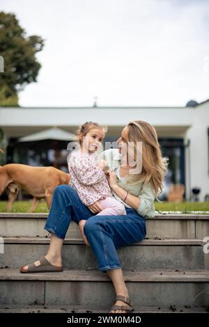 Madre e figlia felici sedute sui gradini Foto Stock