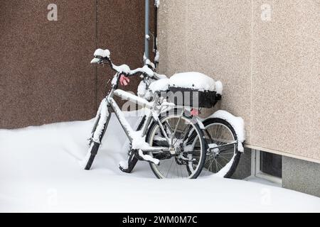 Biciclette alle pareti della casa dopo una nevicata, inverno. Foto Stock