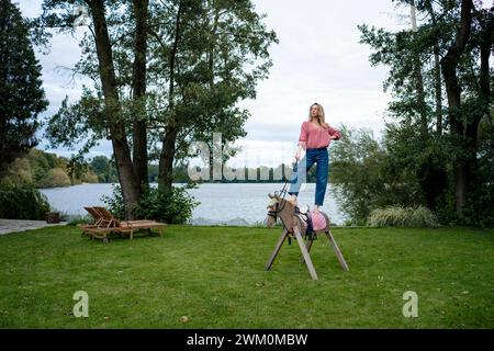 Donna in piedi su un cavallo di legno di fronte al lago Foto Stock