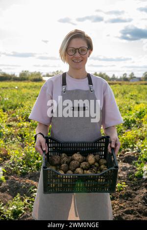 Agricoltore sorridente che detiene casse di patate in azienda Foto Stock