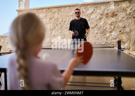 Padre che gioca a ping pong con la figlia in vacanza in villa Foto Stock