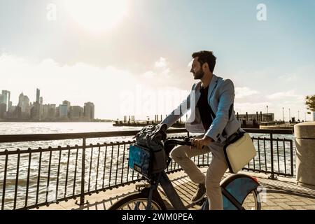 Uomo d'affari in bicicletta sul lungomare della città Foto Stock