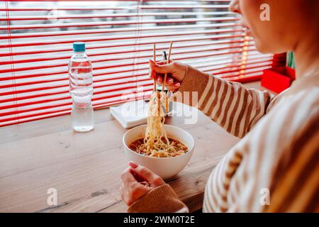 Donna che mangia ramen usando le bacchette al bar Foto Stock